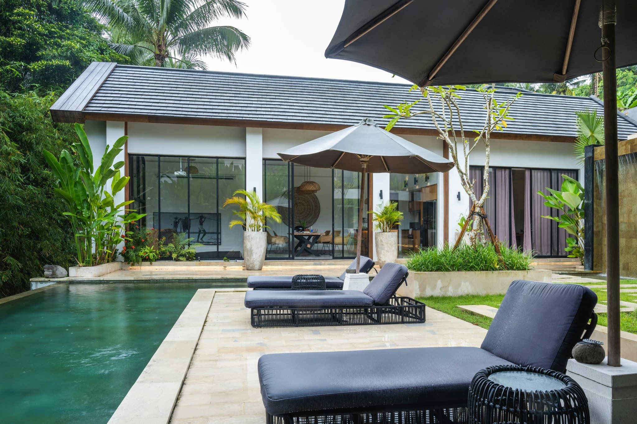 A pool with lounge chairs and an umbrella next to it